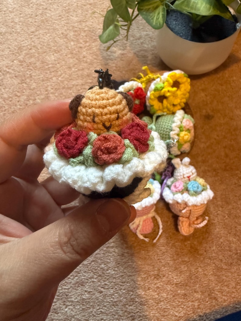 Pu&ograve; includere: Portachiavi a forma di cupcake all'uncinetto. Uno presenta un cane marrone con orecchie marroni e rose rosse. Altri includono un girasole, un coniglietto e composizioni floreali. Ogni portachiavi ha una piccola chiusura in metallo.
