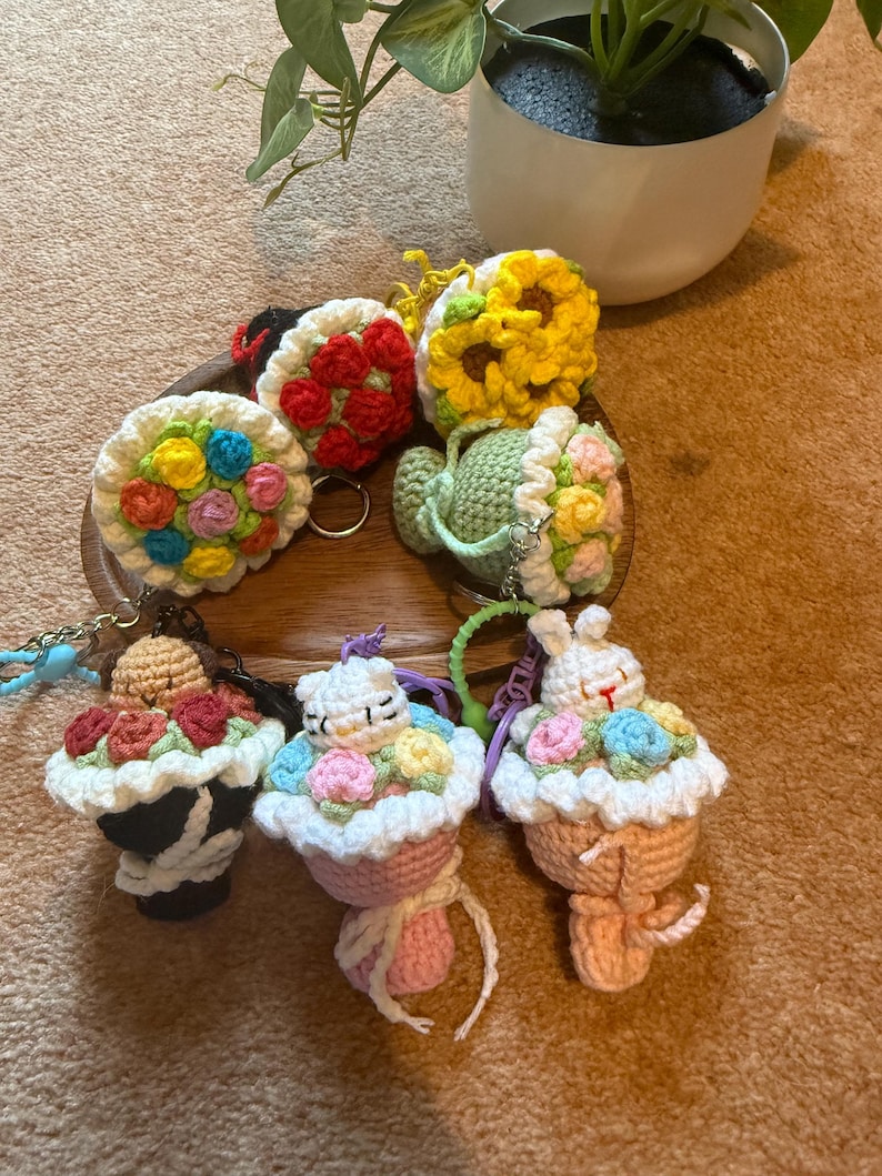 Pu&ograve; includere: Una collezione di portachiavi all'uncinetto fatti a mano in vari design. I portachiavi includono un girasole, una teiera e disegni a forma di cupcake con accenti floreali. La tavolozza dei colori comprende giallo, rosso, rosa e verde.