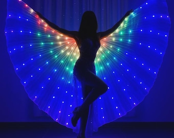 May include: A silhouette of a person wearing a shimmering costume and illuminated wings. The wings are lit with a spectrum of colors, including red, orange, green, and blue, creating a vibrant display. The person is posed with arms outstretched, showcasing the wings.