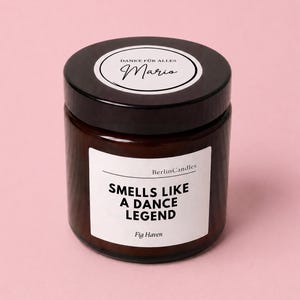 Op de afbeelding: Een bruine glazen potkaars met een zwart deksel. Op het etiket staat "Smells Like A Dance Legend" en "Fig Haven". Het deksel heeft een wit etiket met de tekst "Danke für Alles" en de naam "Mario".