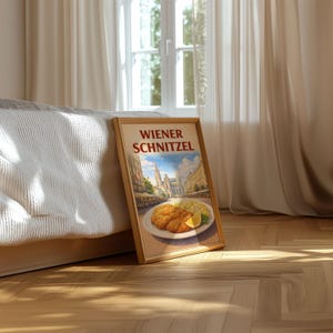 Puede incluir: Un cuadro enmarcado con el texto "WIENER SCHNITZEL". La imagen muestra un plato de schnitzel con una rodaja de limón y puré de patatas, con el telón de fondo de una ciudad europea. El marco es de color marrón claro.