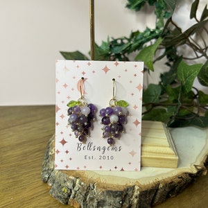 May include: Amethyst grape earrings with gold accents and green leaves. The earrings are on a white card with the text "Bellsngems Est. 2010".