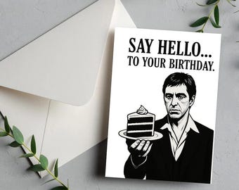 May include: White birthday card with the text "SAY HELLO... TO YOUR BIRTHDAY." and a black and white illustration of a man holding a slice of cake. An envelope is visible to the left.