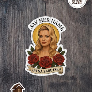 May include: A sticker featuring a portrait of a woman with blonde hair, a halo, and the text "SAY HER NAME." Below the portrait are three red roses and the name "IRYNA ZARUTSKA." The sticker also includes a "SHOP NOW" QR code and the "MADHOUSE DECOR & DESIGNS" logo.