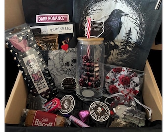 May include: A gift box filled with gothic-themed items. Includes a black t-shirt with a "DARK ROMANCE" sticker, a raven-themed pouch, a glass with a rose design, a bookmark, stickers, candy, and a Biscoff cookie.