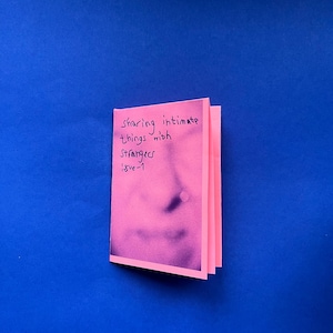 Könnte beinhalten: Ein rosa Heft mit dem Text "sharing intimate things with strangers issue 1" auf dem Cover. Das Heft ist geöffnet und zeigt ein verschwommenes Gesichts-Bild. Der Hintergrund ist einfarbig blau.