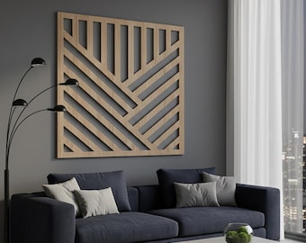 May include: A square wooden wall art piece featuring a geometric pattern of intersecting vertical and diagonal slats. The light brown wood panel is mounted on a dark gray wall above a dark blue sofa, creating a structured and linear visual display.