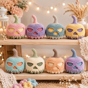 May include: Eight crocheted pumpkins arranged on two wooden shelves. Each pumpkin features a carved-out face design with a stem on top. The pumpkins are crafted in various pastel colors including pink, purple, blue, yellow, green, and orange.