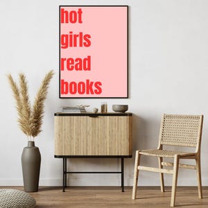 Könnte beinhalten: Ein rosa Poster mit dem Text "hot girls read books" in roten Buchstaben.