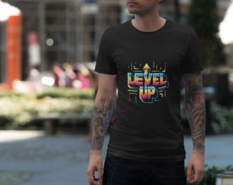 May include: Black t-shirt with a colorful "LEVEL UP" graphic. The design features an upward arrow and text in a retro, neon style. The shirt is short-sleeved and appears to be made of cotton.