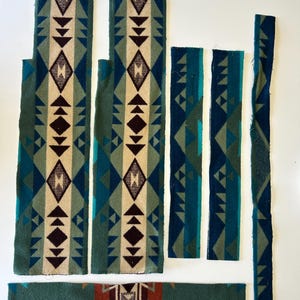 May include: Six rectangular fabric strips featuring a geometric pattern in shades of teal, dark green, cream, and deep brown. The pieces vary in width and length, displaying repeating diamond and triangular motifs across the woven textile surface.
