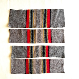 May include: Four rectangular strips of grey felted fabric arranged horizontally. Each strip features a central vertical pattern consisting of a wide red stripe, a thin dark green stripe, a thin yellow stripe, and a thin tan stripe on a grey background.