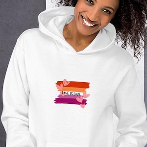 May include: White hoodie with a front pocket and a hood. The design features the text "LOVE IS LOVE" in a cursive font, with a horizontal stripe design in orange, red, and purple, and small pink hearts.