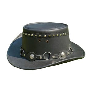 May include: Black leather cowboy hat with a flat top and a wide brim. The hat features silver-colored metal studs around the crown and a decorative band with silver-colored embellishments. The hat is designed for sun protection and style.