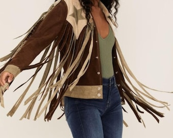 Könnte beinhalten: Braune Wildlederjacke mit beigen Fransen und Sternakzenten. Die Jacke hat einen Kragen, Knöpfe und lange Fransen an den Ärmeln und der Brust. Eine stilvolle Jacke im Western-Stil.