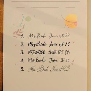May include: A cream-colored paper with handwritten calligraphy. The text reads "Mrs. Bride June 1st 23" repeated five times. Decorative watercolor accents in pink, blue, and yellow are scattered around the text.
