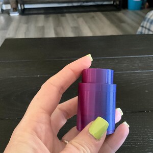 Puede incluir: Un tap&oacute;n de botella morado y azul con un acabado liso y brillante.