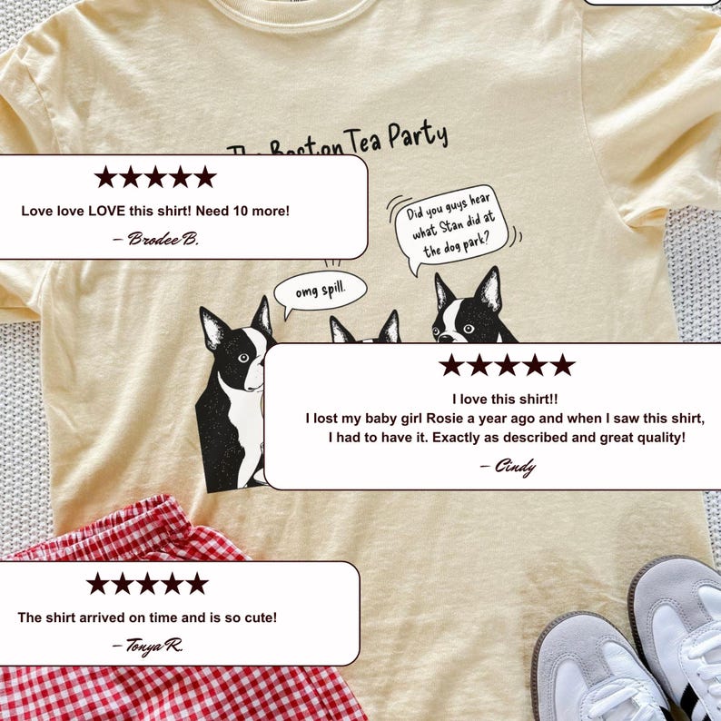May include: A pale yellow t-shirt featuring a black and white graphic of three Boston Terrier dogs with speech bubbles that read The Boston Tea Party, omg spill, and Did you guys hear what Stan did at the dog park? The shirt is paired with red gingham shorts.