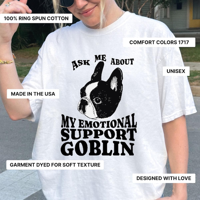 May include: White unisex t-shirt with a black and white graphic of a French bulldog and the text "Ask Me About My Emotional Support Goblin." The shirt is made of 100% ring-spun cotton and garment-dyed for a soft texture. Designed with love and made in the USA.