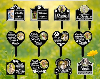 May include: Black memorial garden stakes with various dog photos, paw prints, and text. The stakes are in different shapes, including rectangles and hearts, with phrases like "In loving memory" and "Forever in my heart."
