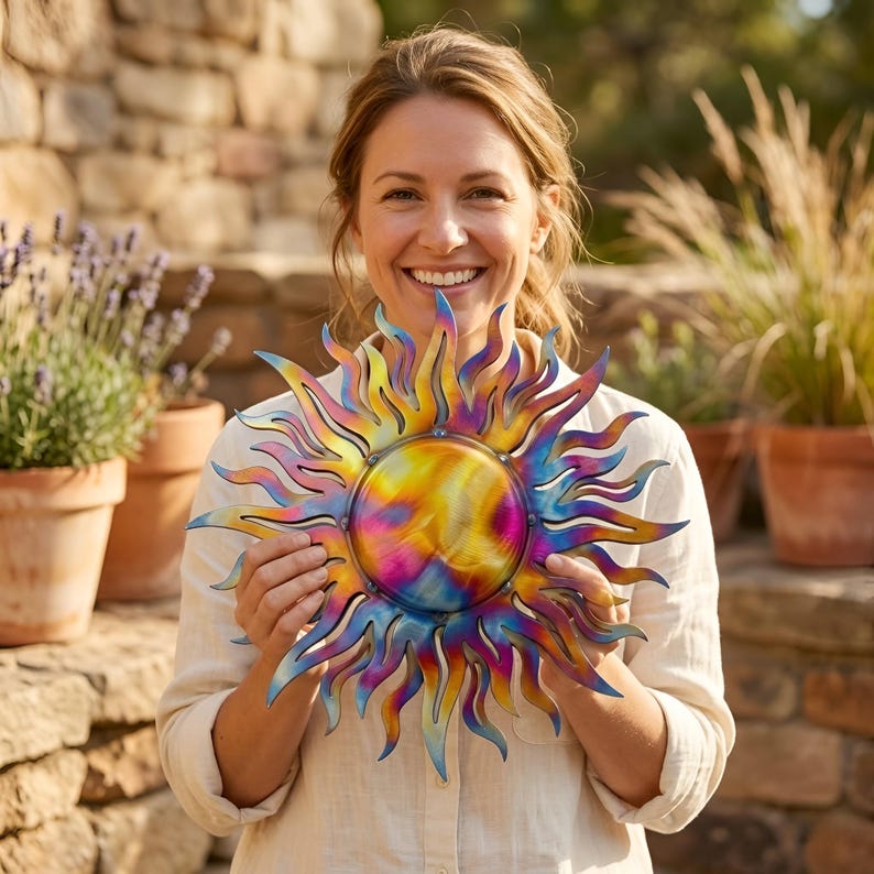 Pu&ograve; includere: Un'opera d'arte da parete a forma di sole in metallo multicolore e vibrante. Il sole ha un centro circolare con raggi radianti nelle tonalit&agrave; di giallo, rosa, blu e viola. L'opera &egrave; tenuta da una persona di fronte a un muro di pietra e piante in vaso.