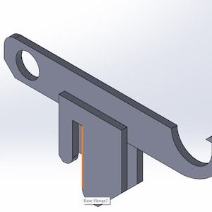 Könnte beinhalten: Eine graue Metallhalterung mit einem kreisförmigen Loch an einem Ende und einem gebogenen Haken am anderen. Die Halterung hat eine rechteckige Basis mit einem Schlitz und dem Text "Base-Flange3".