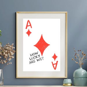 May include: Framed art print featuring a red Ace of Diamonds playing card design on a white background. The text "HOW LUCKY ARE WE?" is included. The artwork is displayed in a gold frame.