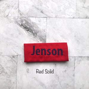 Personalized red handle wrap, with navy embroidery your choice of name or monogram. Our handle wraps measure  4.5 inches by 5.25 inches and are 100% cotton with a strip of Velcro to attach securely around any handle.