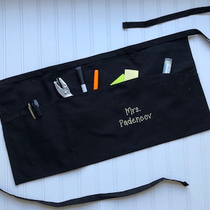May include: Black apron with multiple pockets, a name tag that reads "Mrs. Padencov", and various tools and supplies.