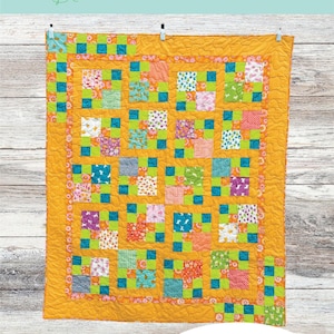 Puede incluir: Un patrón de colcha llamado "Semi Charmed" de Alee B Creative. La colcha está hecha de cuadrados coloridos en tonos de naranja, rosa, verde y azul. La colcha está colgada en una pared de madera.