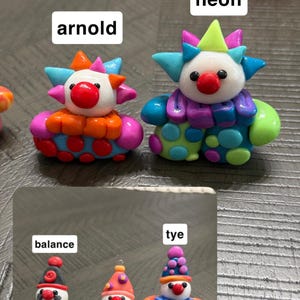 May include: Five small clown figurines made of colourful clay. The top two are labelled Arnold and neon. The bottom three are labelled balance, sunshine, and tye. Each clown features a white face, a red nose, and a unique colourful outfit with patterns.