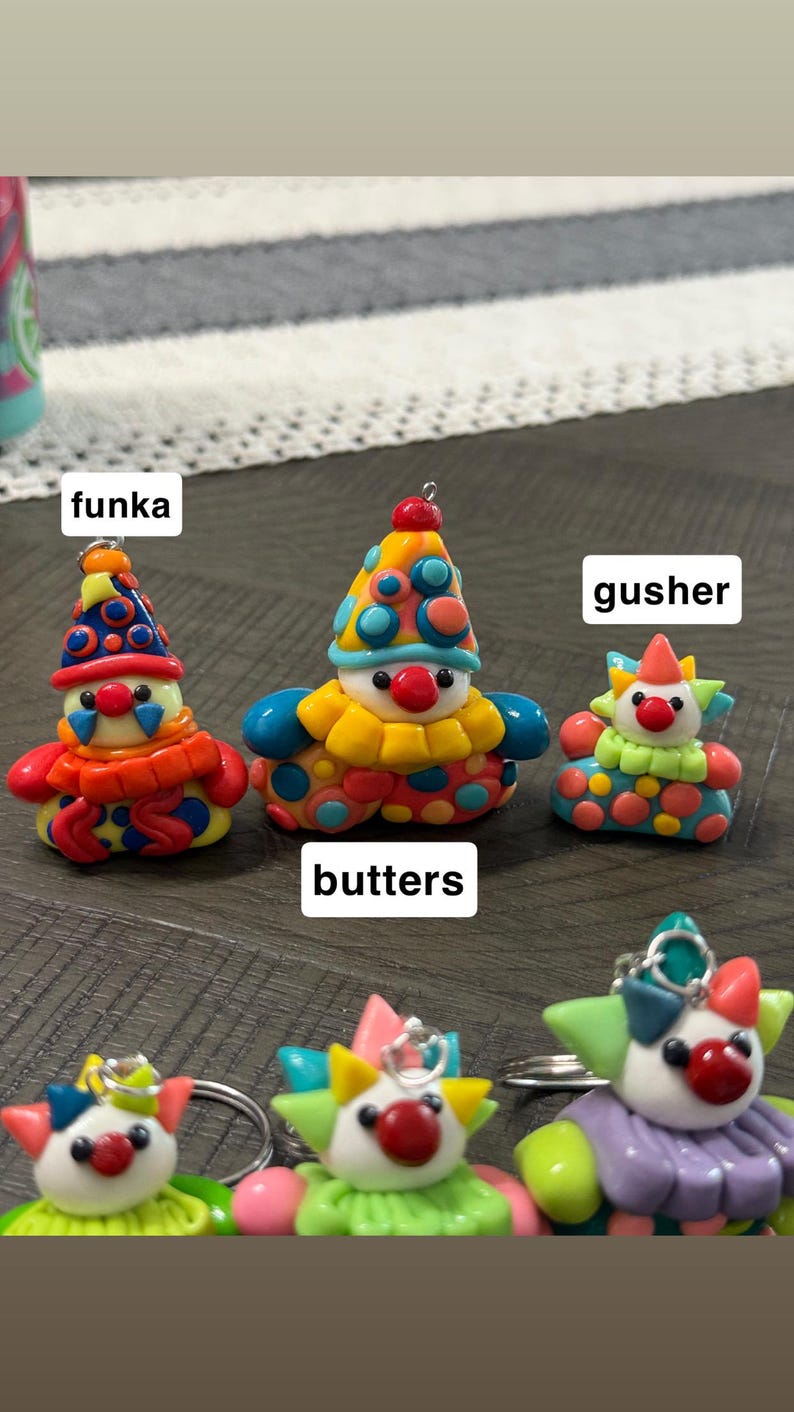 May include: A collection of colourful clown figurines made of clay, featuring various patterns and designs. The figurines are labelled with the names funka, butters, and gusher. Each clown has a red nose, a pointed hat, and a ruffled collar.
