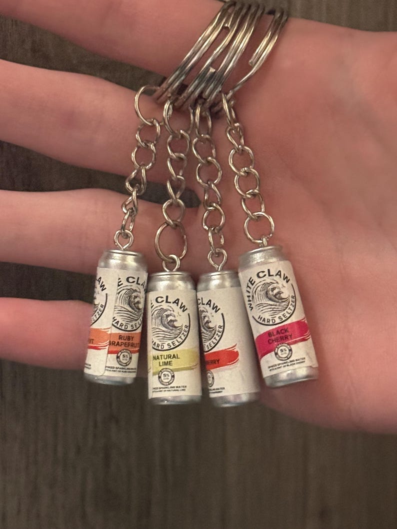 Puede incluir: Llaveros de mini latas de White Claw hard seltzer. Cada llavero presenta un sabor diferente: Ruby Grapefruit, Natural Lime, Berry y Black Cherry. Las latas est&aacute;n unidas a una cadena y un llavero plateados.