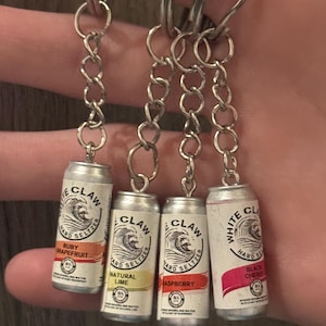 Puede incluir: Cuatro llaveros en miniatura de latas de White Claw hard seltzer. Cada lata es plateada con un logotipo de ola blanca y etiquetas de sabor: Ruby Grapefruit, Natural Lime, Raspberry y Black Cherry. Los llaveros tienen eslabones de cadena plateados y llaveros.