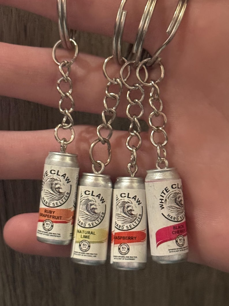 Puede incluir: Cuatro llaveros en miniatura de latas de White Claw hard seltzer. Cada lata es plateada con un logotipo de ola blanca y etiquetas de sabor: Ruby Grapefruit, Natural Lime, Raspberry y Black Cherry. Los llaveros tienen eslabones de cadena plateados y llaveros.
