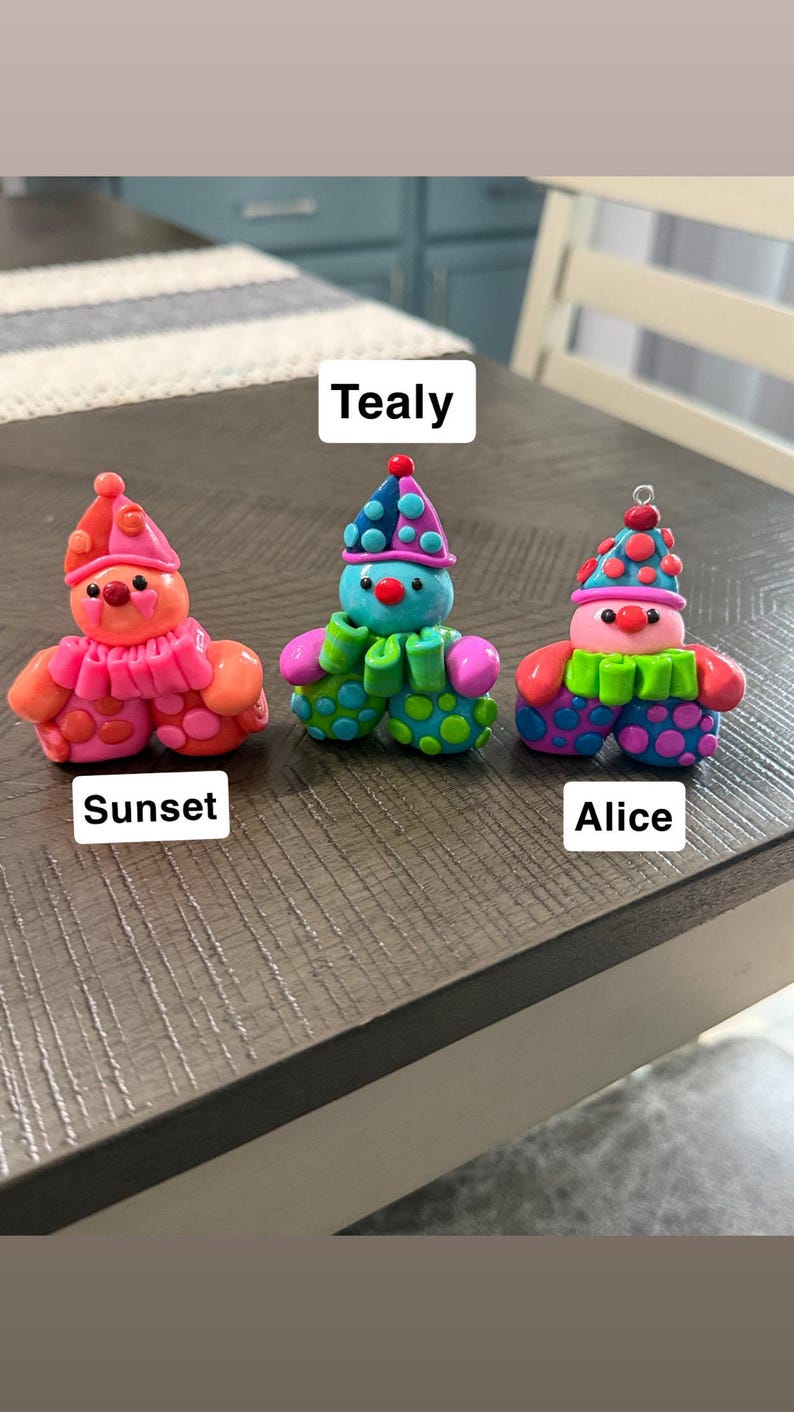 May include: Three small clown figurines labelled Sunset, Tealy, and Alice. Sunset is orange and pink with polka dots. Tealy is blue, green, and purple with polka dots. Alice is pink, blue, and green with polka dots and a small metal loop on top.