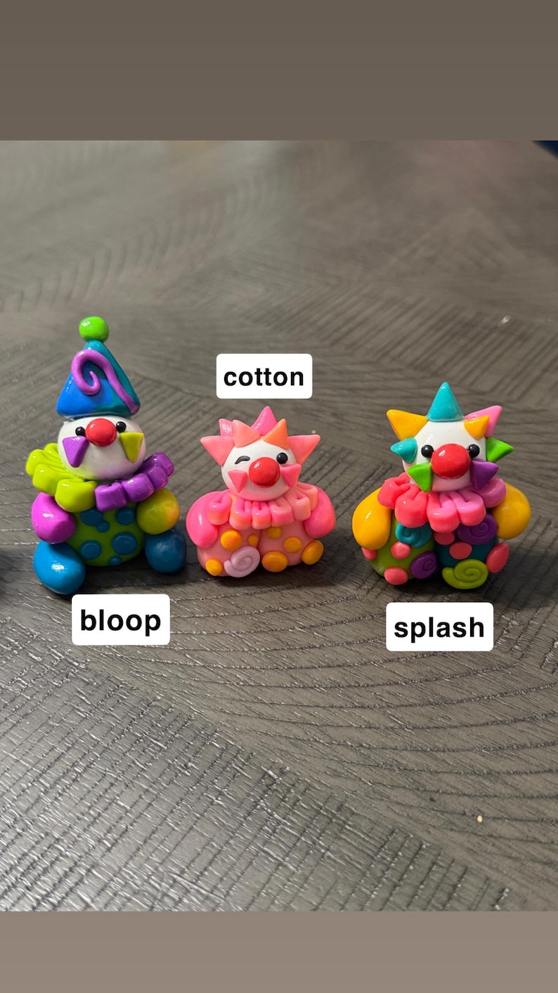 May include: Three small clown figurines made of colourful clay. The left figure is labelled bloop, wearing a blue hat and green and purple ruff. The centre figure is labelled cotton, in shades of pink and orange. The right figure is labelled splash.
