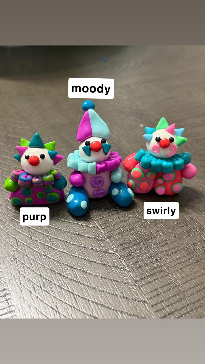 May include: Three small clown figurines made of colourful clay. The left one is labelled purp and has purple, green, and blue patterns. The centre one is labelled moody and features blue, purple, and pink colours. The right one is labelled swirly.