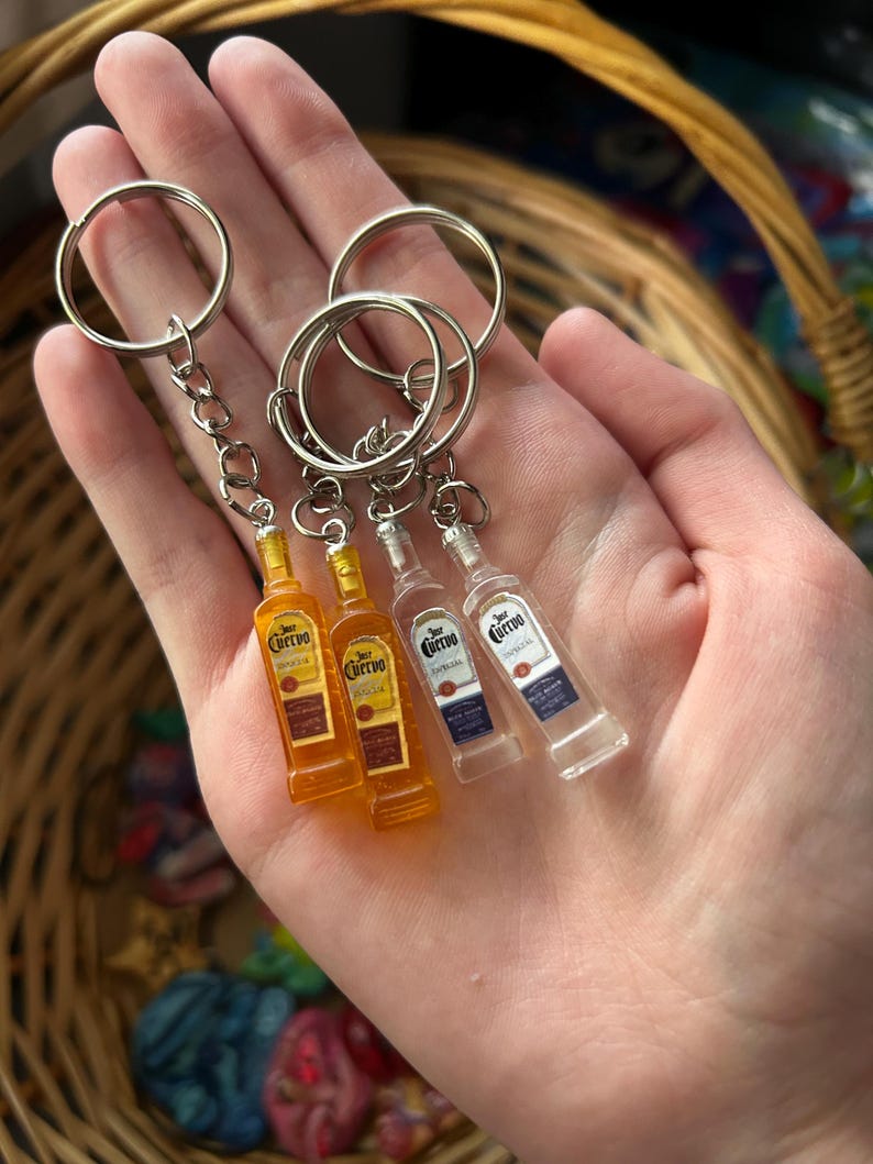 Puede incluir: Llaveros de botellas de tequila en miniatura. Dos botellas de color &aacute;mbar y dos botellas transparentes con el logo "Cuervo". Cada llavero tiene un anillo y una cadena plateados.