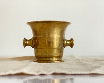 Antique heavy brass mortar. Vintage druggist vessel and kitchen tool for crushing herbs and spices. Rustic kitchen decor.