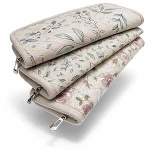 Pode incluir: Três bolsas de tecido acolchoado bege com estampas florais e de folhas. Cada bolsa tem um zíper prateado. As duas bolsas superiores apresentam folhas verdes e azuis, enquanto a inferior exibe rosas cor-de-rosa.