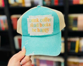 Cappello a coda di cavallo color verde acqua con scritta "Coffee Books Happy Patch"