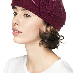 K&ouml;nnte beinhalten: Ein weiches, weinrotes Stirnband mit einer gro&szlig;en, paillettenbesetzten Blume. Die Blume hat geschichtete Bl&uuml;tenbl&auml;tter und eine dunkelviolette Umrandung. Das Stirnband wird von einer Person getragen, die ein wei&szlig;es T-Shirt tr&auml;gt.