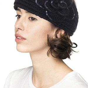 K&ouml;nnte beinhalten: Schwarzes Stirnband aus Strick mit einem Blumendesign und silbernen Pailletten. Die Person tr&auml;gt ein wei&szlig;es T-Shirt.