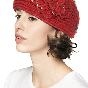 K&ouml;nnte beinhalten: Ein rotes Strickstirnband mit einer gro&szlig;en, paillettenbesetzten Blume. Das Stirnband besteht aus einem dicken, strukturierten Garn. Die Blume besteht aus mehreren Bl&uuml;tenbl&auml;ttern und ist mit kleinen, gl&auml;nzenden Pailletten verziert.