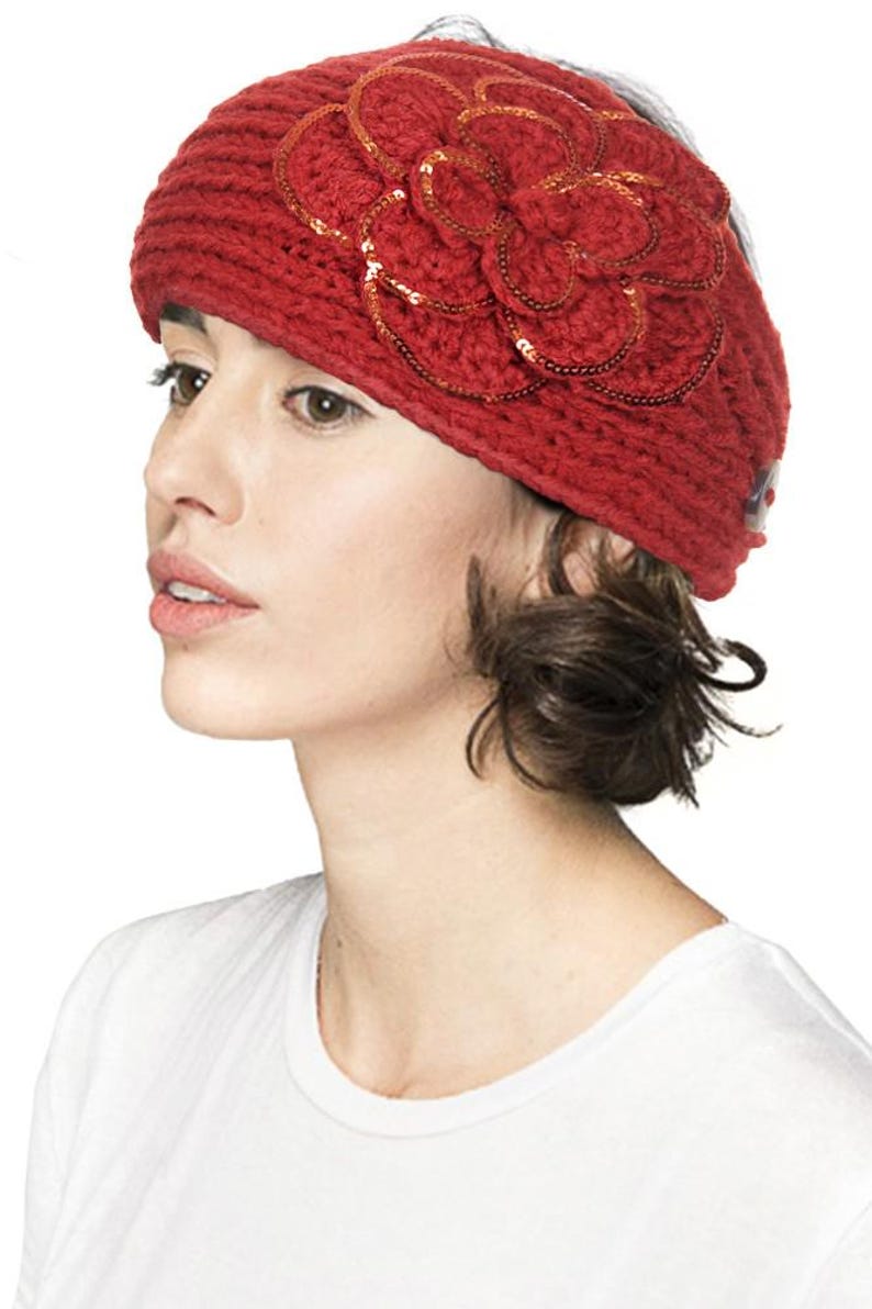 K&ouml;nnte beinhalten: Ein rotes Strickstirnband mit einer gro&szlig;en, paillettenbesetzten Blume. Das Stirnband besteht aus einem dicken, strukturierten Garn. Die Blume besteht aus mehreren Bl&uuml;tenbl&auml;ttern und ist mit kleinen, gl&auml;nzenden Pailletten verziert.