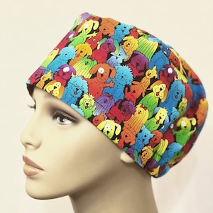 May include: A colorful surgical scrub hat with a pattern of cartoon dogs in various colors and poses. The hat is made of a soft, breathable fabric and is designed to be comfortable to wear for long periods of time.