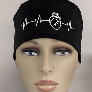May include: Black scrub hat with a white heart and EKG line graphic.