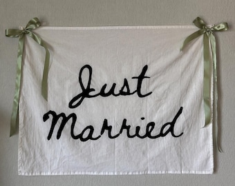 Pancarta de tela pintada a mano con la inscripción "Recién casados", elegante recuerdo de boda.