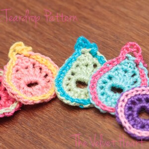 Peut inclure: Cinq formes de larmes en crochet de diff&eacute;rentes couleurs. Les larmes sont roses, jaunes, vertes, bleues et violettes. Les larmes sont dispos&eacute;es en rang&eacute;e de gauche &agrave; droite. Le texte "Crochet Teardrop Pattern" est visible en haut de l'image.